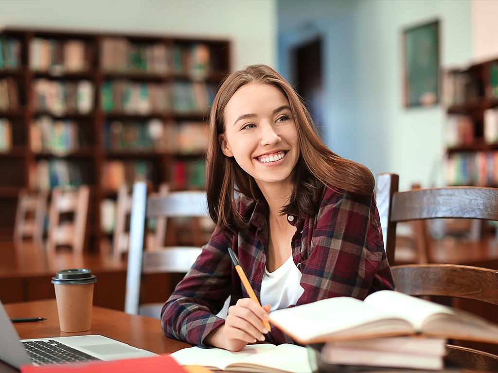 Student smiling while studying in a library
